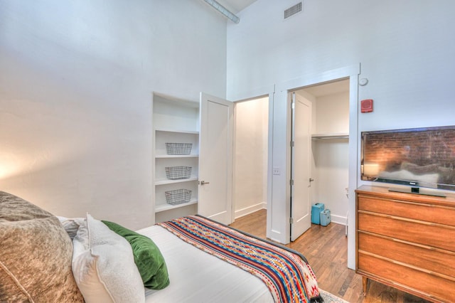 bedroom featuring hardwood / wood-style floors and a towering ceiling