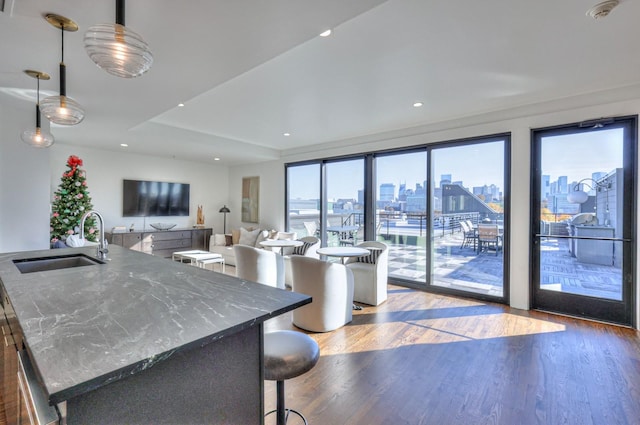 kitchen featuring sink, a breakfast bar area, dark stone countertops, dark hardwood / wood-style flooring, and decorative light fixtures