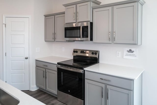 kitchen featuring stainless steel appliances, dark hardwood / wood-style floors, and gray cabinetry