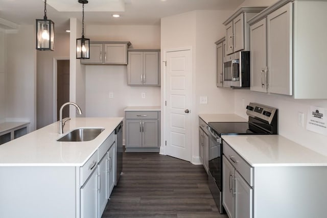 kitchen with pendant lighting, sink, gray cabinets, appliances with stainless steel finishes, and a center island with sink