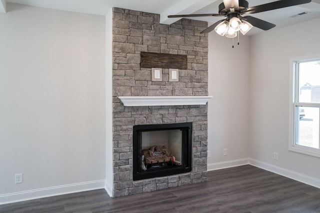 unfurnished living room featuring beamed ceiling, dark wood-type flooring, a large fireplace, and a healthy amount of sunlight