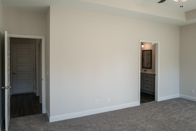 unfurnished bedroom with dark colored carpet and ensuite bathroom