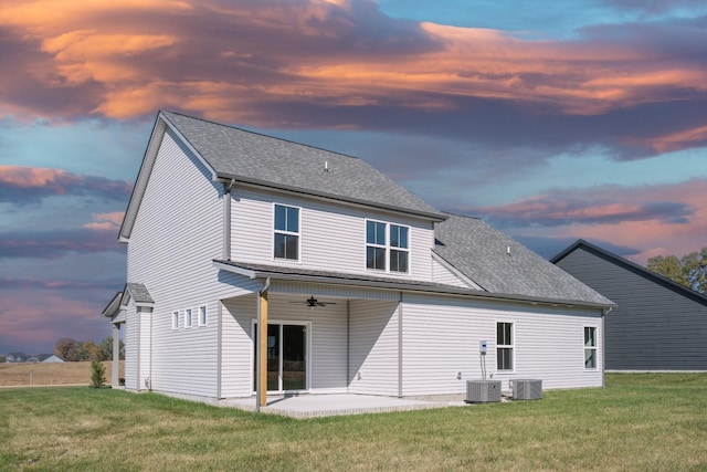 back house at dusk with a yard, a patio, ceiling fan, and central air condition unit