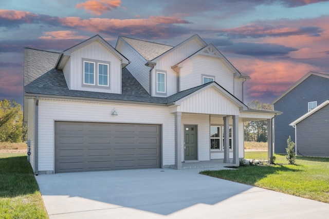 view of front of property featuring a garage, covered porch, and a lawn