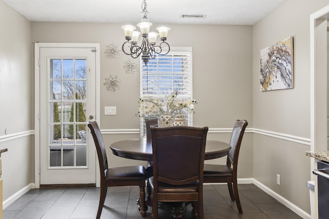 dining area with dark tile patterned flooring and a chandelier