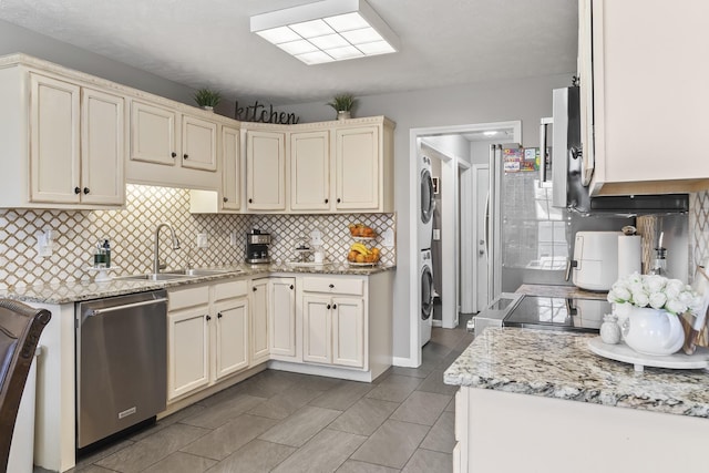 kitchen featuring stacked washer / drying machine, sink, tasteful backsplash, dishwasher, and cream cabinetry