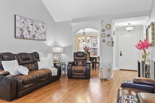 living room with an inviting chandelier, crown molding, wood-type flooring, and vaulted ceiling