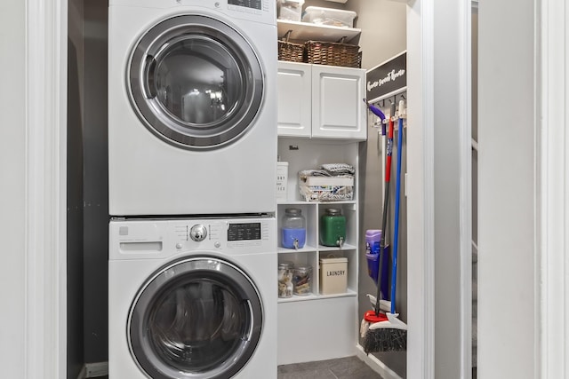 washroom with cabinets, stacked washing maching and dryer, and tile patterned flooring