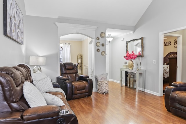 living room featuring lofted ceiling, crown molding, and light wood-type flooring