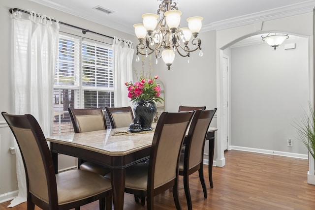 dining room with ornamental molding, hardwood / wood-style floors, and a chandelier