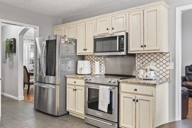 kitchen featuring appliances with stainless steel finishes, backsplash, and cream cabinetry