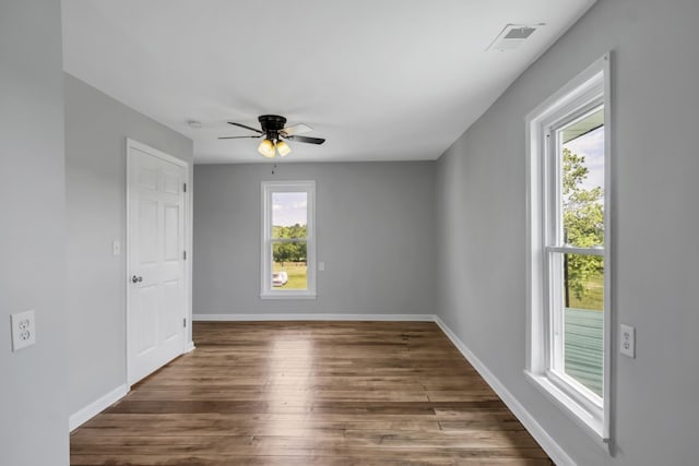 unfurnished room with a wealth of natural light, dark hardwood / wood-style floors, and ceiling fan