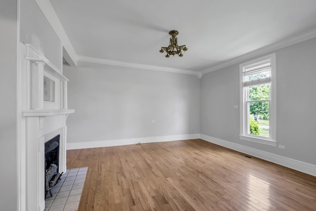 unfurnished living room with ornamental molding, a tile fireplace, and light hardwood / wood-style flooring