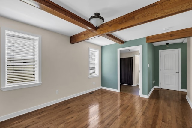 empty room featuring beam ceiling and dark hardwood / wood-style floors