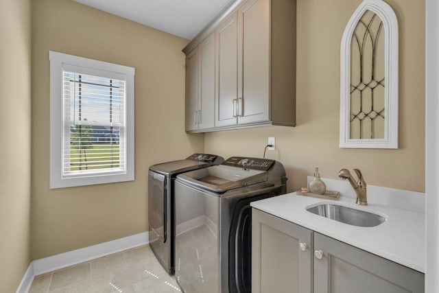 clothes washing area with cabinets, sink, light tile patterned floors, and independent washer and dryer