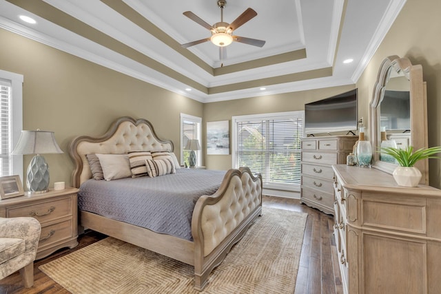 bedroom featuring hardwood / wood-style flooring, ceiling fan, ornamental molding, and a tray ceiling