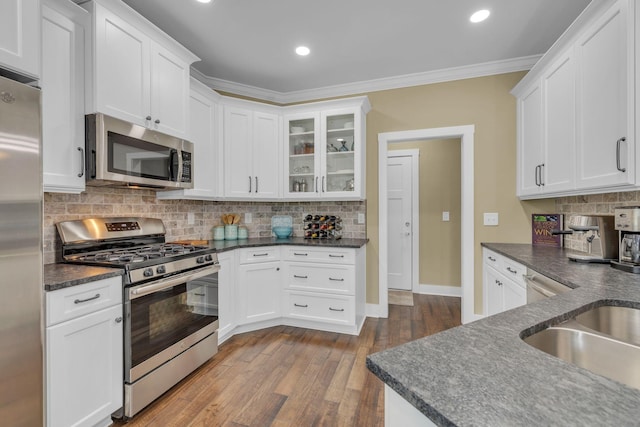 kitchen with stainless steel appliances, ornamental molding, and white cabinets