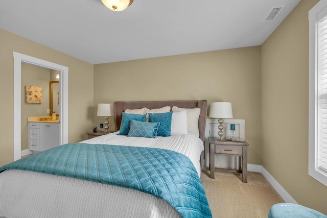 bedroom with light colored carpet and connected bathroom