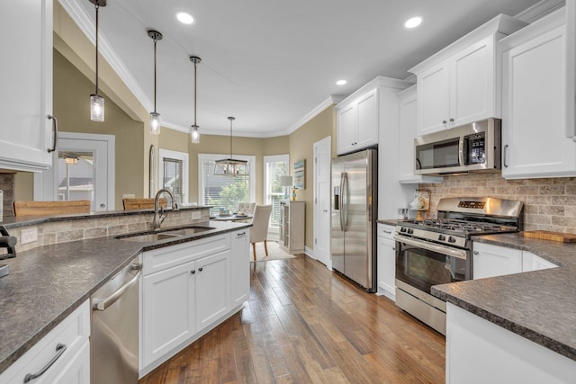 kitchen featuring hanging light fixtures, appliances with stainless steel finishes, sink, and white cabinets