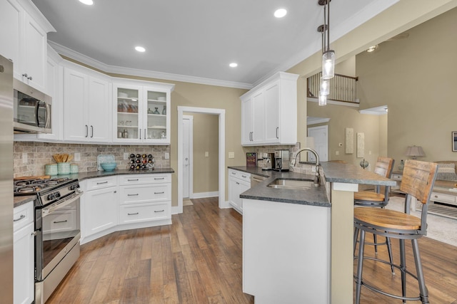 kitchen featuring sink, hanging light fixtures, appliances with stainless steel finishes, a kitchen breakfast bar, and kitchen peninsula