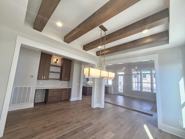 kitchen featuring dark wood-type flooring, dark brown cabinetry, a breakfast bar area, decorative light fixtures, and beamed ceiling