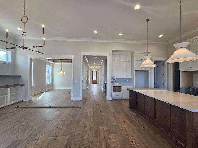 kitchen with hardwood / wood-style flooring, ornamental molding, tasteful backsplash, and white cabinets