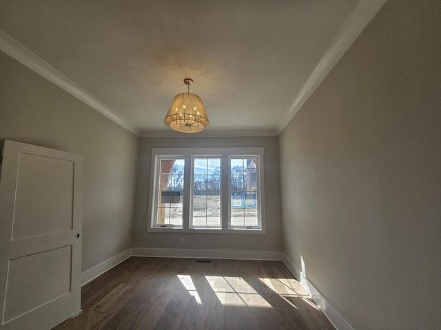 spare room featuring dark hardwood / wood-style flooring, crown molding, and an inviting chandelier