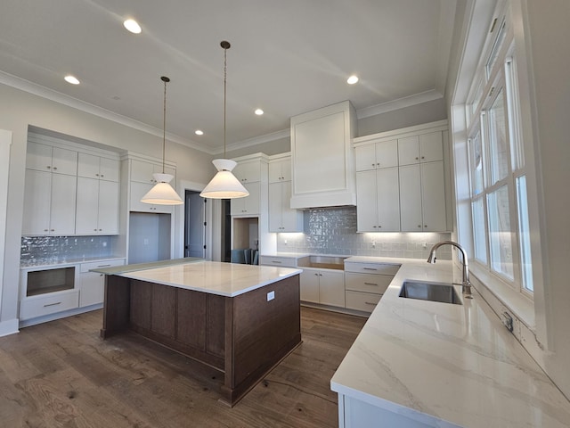 kitchen featuring pendant lighting, sink, white cabinets, a large island, and light stone countertops