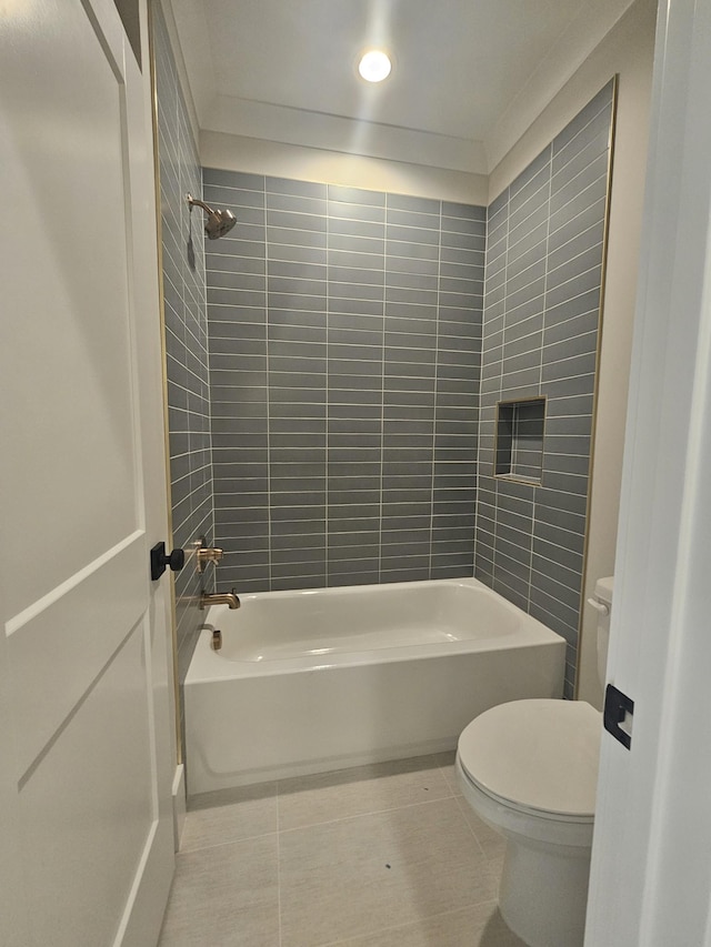 bathroom featuring tile patterned flooring, tiled shower / bath combo, and toilet