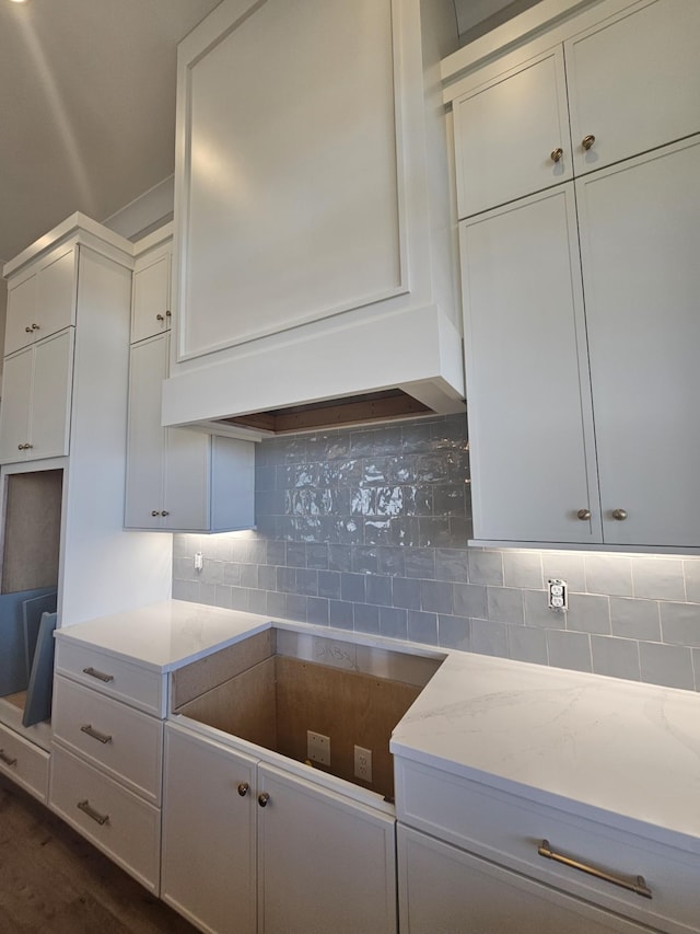 kitchen with decorative backsplash, light stone countertops, and white cabinets