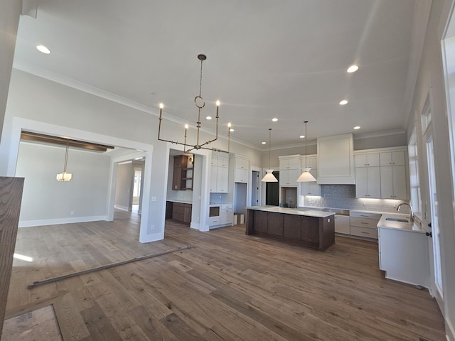 kitchen with a large island, sink, pendant lighting, dark hardwood / wood-style floors, and white cabinets