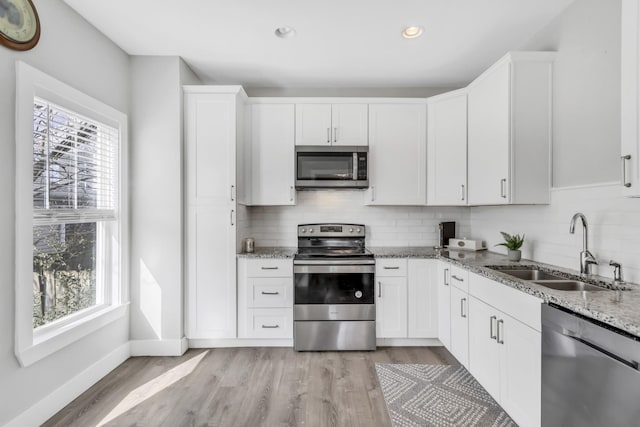 kitchen featuring stainless steel appliances, white cabinetry, and sink