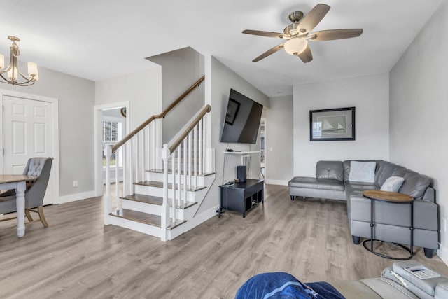 living room with ceiling fan with notable chandelier and light hardwood / wood-style floors