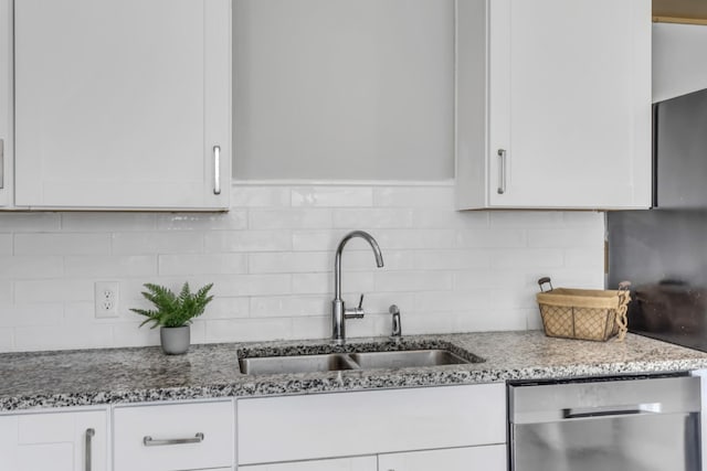 kitchen with white cabinetry, stainless steel dishwasher, sink, and light stone counters