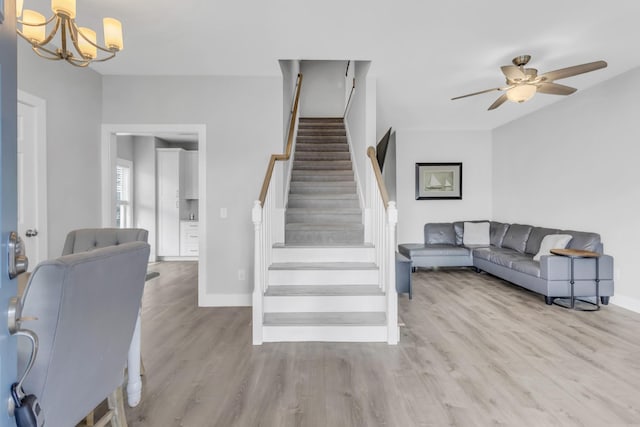 staircase featuring hardwood / wood-style flooring and ceiling fan with notable chandelier