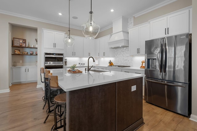 kitchen with custom exhaust hood, sink, white cabinets, and stainless steel fridge