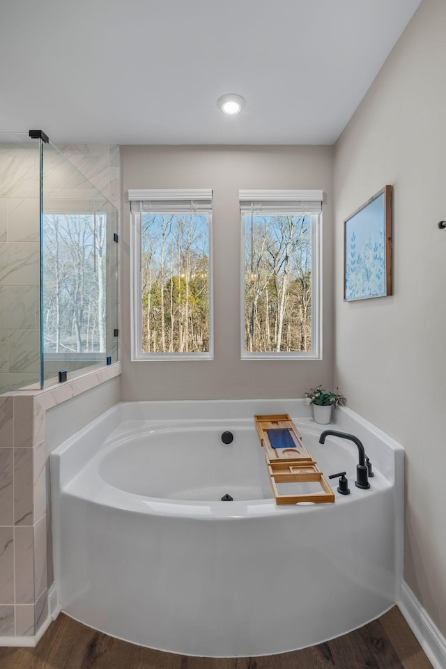 bathroom with wood-type flooring and a tub to relax in