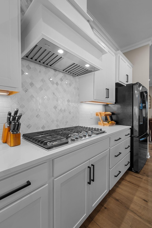 kitchen featuring ornamental molding, dark hardwood / wood-style flooring, custom range hood, stainless steel gas stovetop, and white cabinets