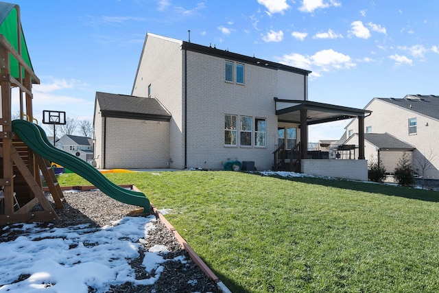 rear view of property featuring a playground and a yard