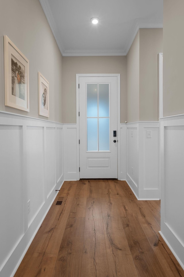 entryway with ornamental molding and light hardwood / wood-style flooring