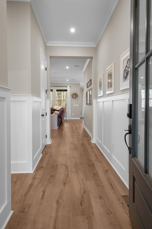 hallway with crown molding and light hardwood / wood-style flooring