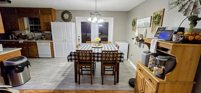 dining space featuring light wood-type flooring, baseboards, and a chandelier