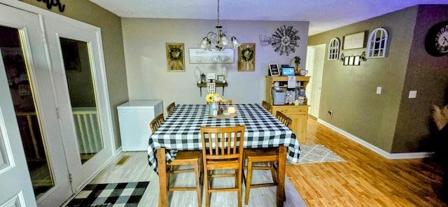 dining space with visible vents, an inviting chandelier, light wood-style flooring, and baseboards