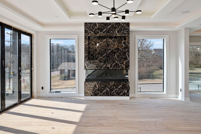 interior space with a tray ceiling, light hardwood / wood-style flooring, and a chandelier