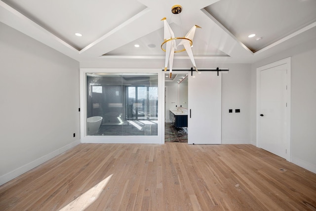 empty room with hardwood / wood-style flooring, a barn door, and a raised ceiling