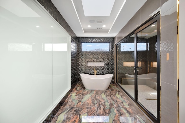 bathroom with a tray ceiling, plus walk in shower, and tile walls