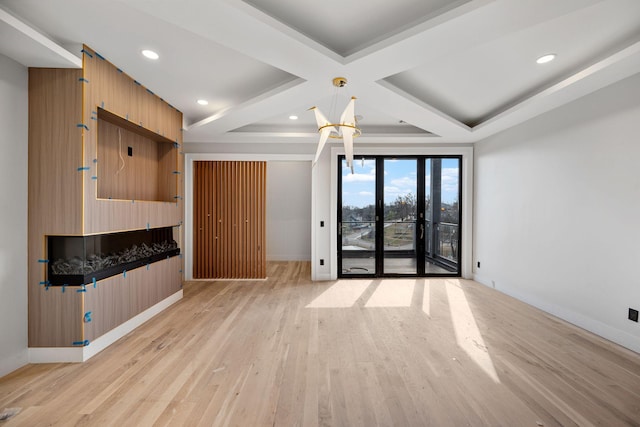 unfurnished living room with beamed ceiling, coffered ceiling, and light hardwood / wood-style floors