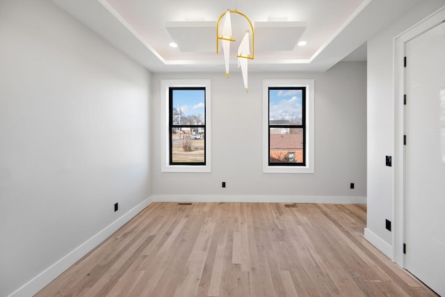 empty room with light hardwood / wood-style flooring and a raised ceiling