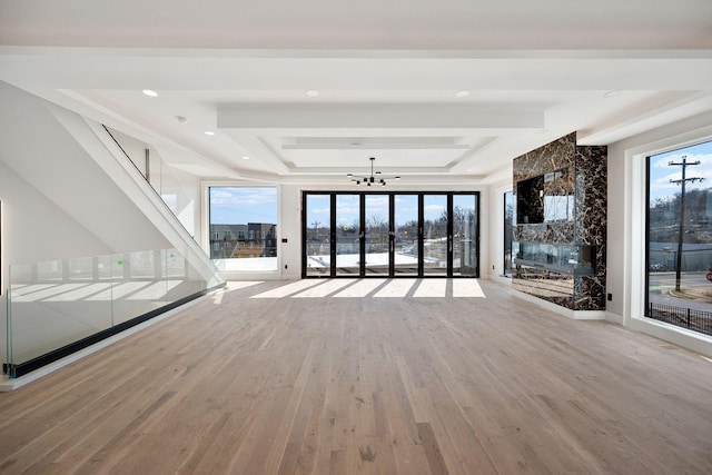 unfurnished living room featuring a raised ceiling, plenty of natural light, hardwood / wood-style floors, and a fireplace