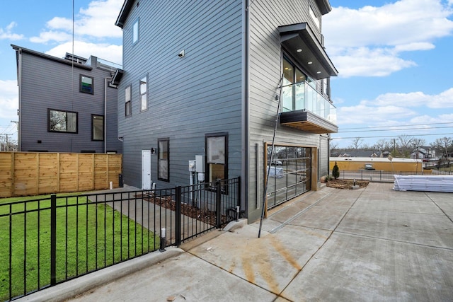 view of side of property with a balcony, a garage, and a lawn